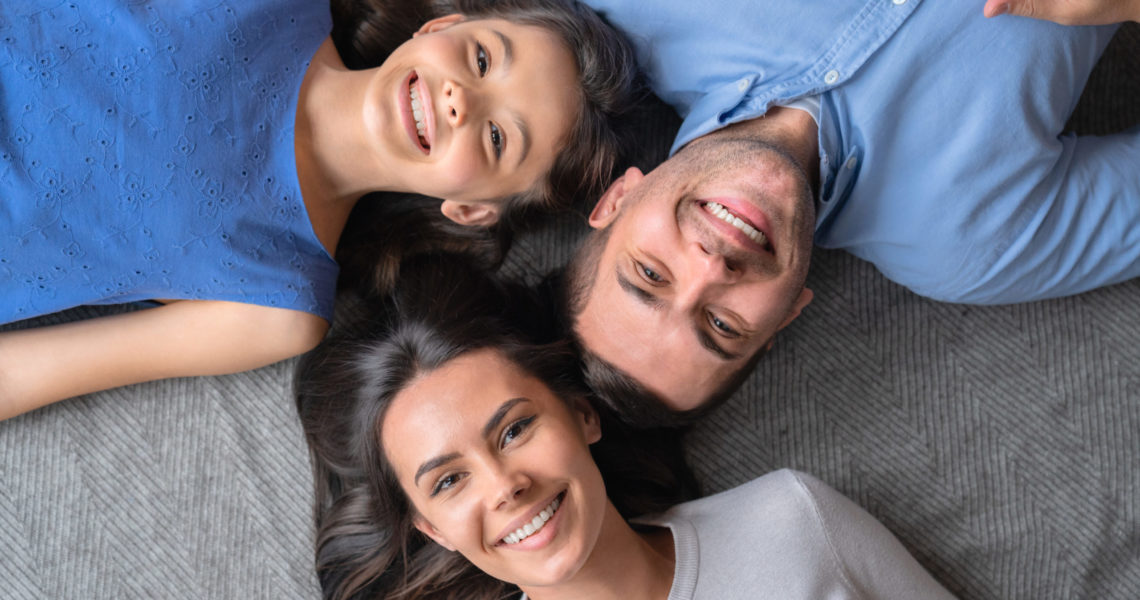 Happy family concept. Top view of happy family of three bonding to each other and smiling