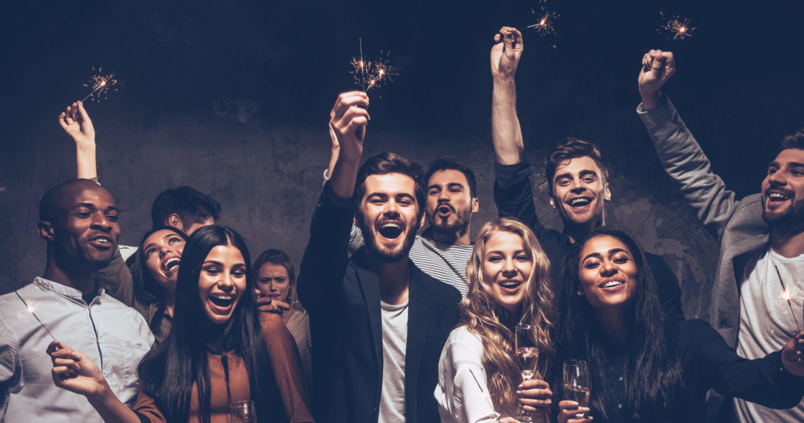 Party with friends. Group of cheerful young people carrying sparklers and champagne flutes