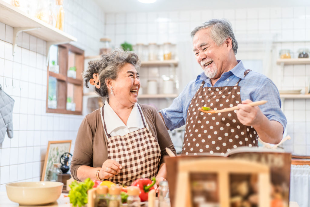 Asian senior elder couple cooking salad dish with happiness and smile enjoy retirement life together