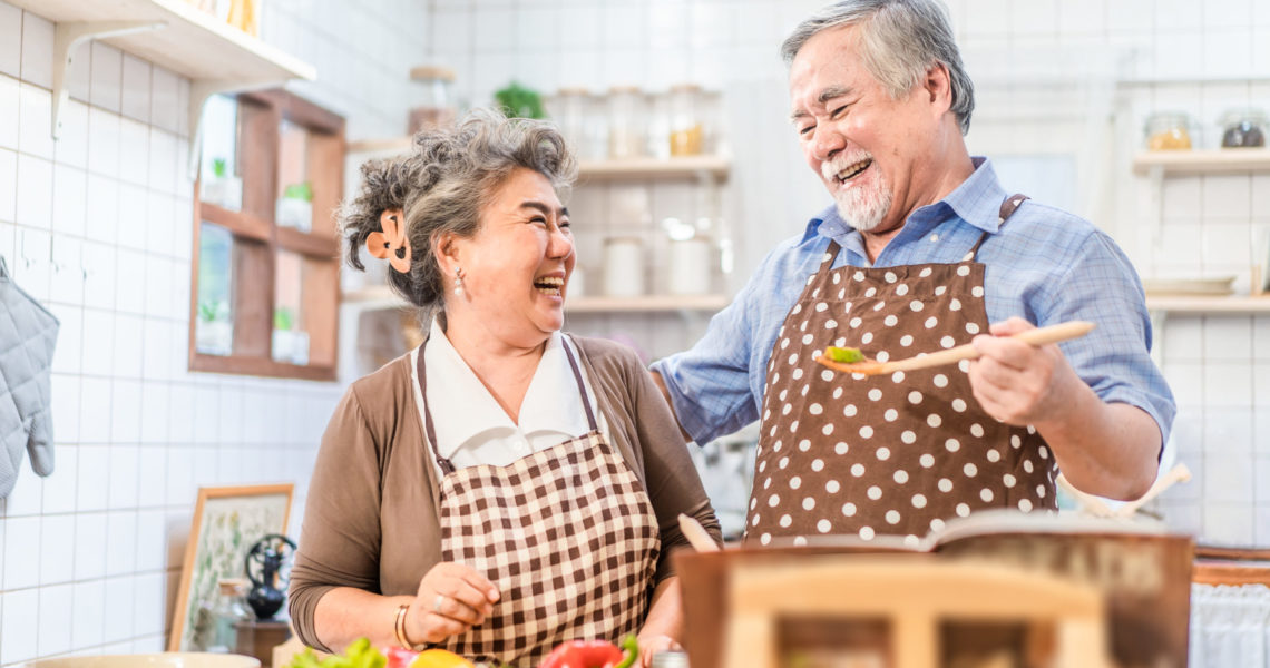 Asian senior elder couple cooking salad dish with happiness and smile enjoy retirement life together